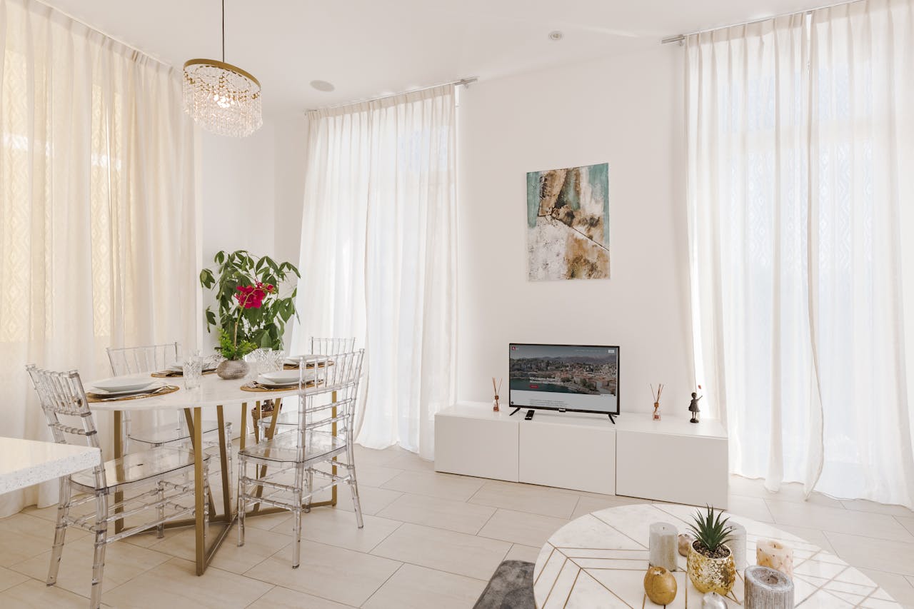 Elegant dining room with white decor, clear chairs, and modern design.